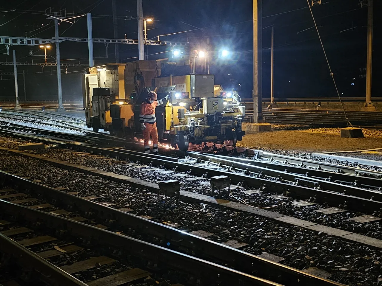 Engin de chantier et équipe au travail de nuit sur la voie